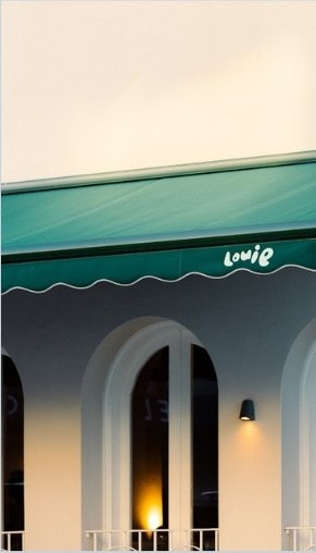 The green awning and arched windows of Louie, Coogee, at dusk.
